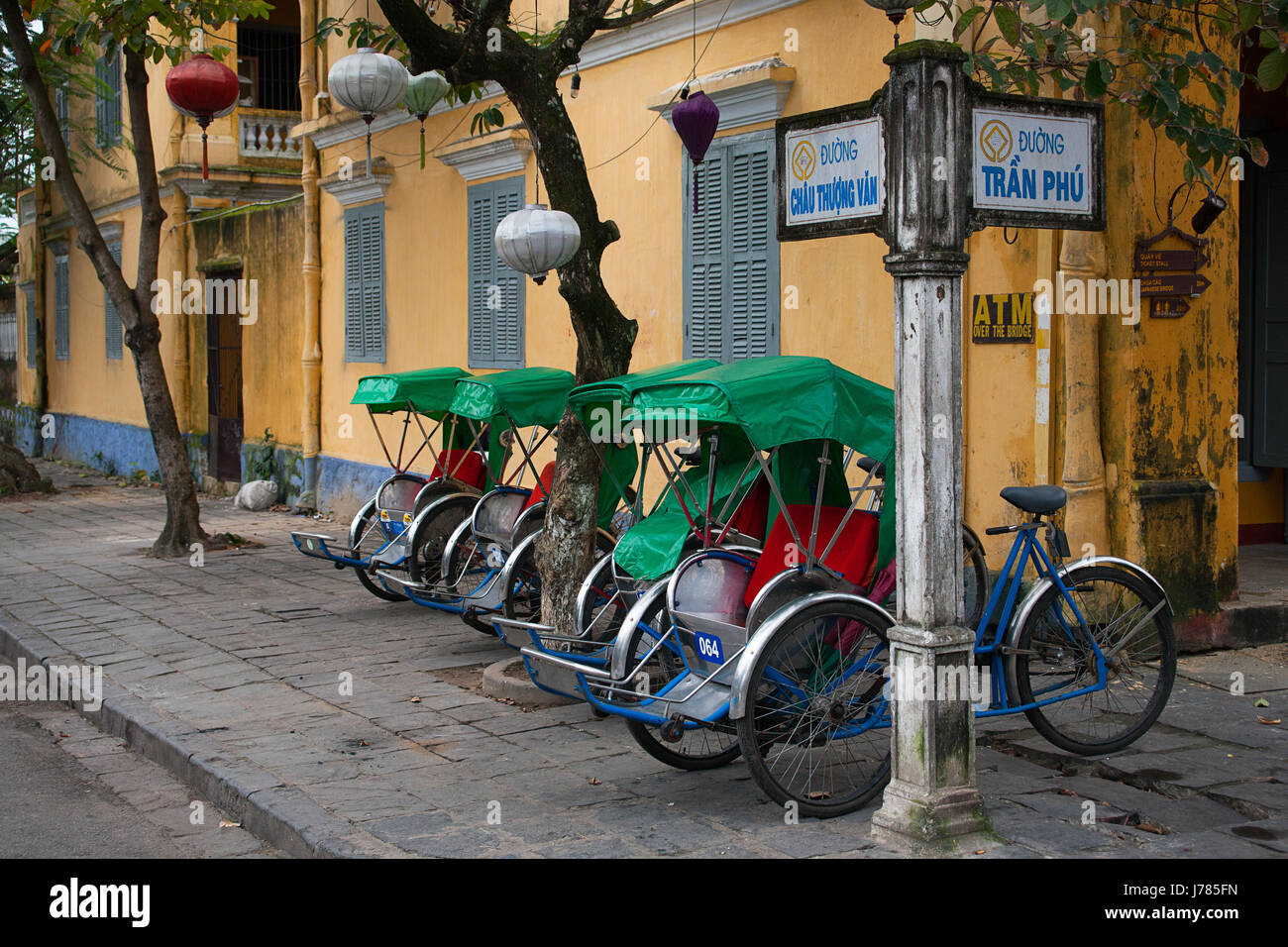 Un gruppo di tre ruote dei carrelli in taxi la linea della strada di Hoi An, Vietnam Foto Stock