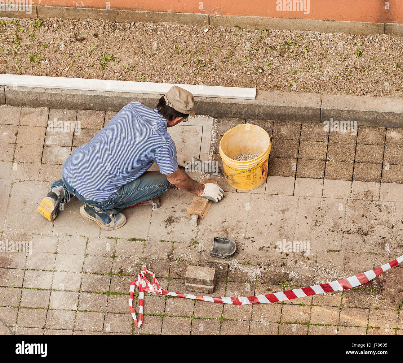 Muratore al lavoro la posa di blocchi di pietra di pavimentazione. Foto Stock