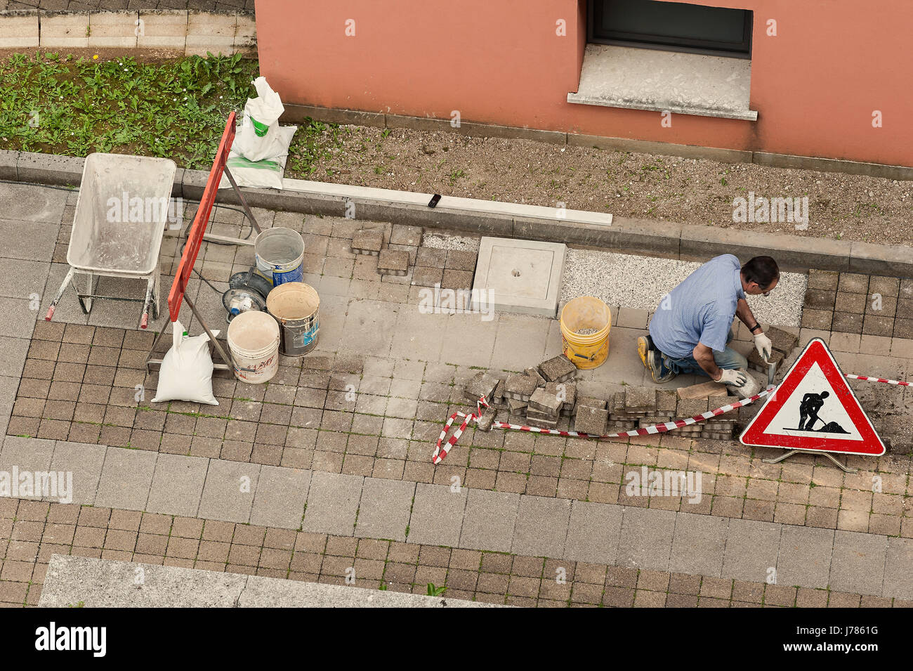 Muratore al lavoro la posa di blocchi di pietra di pavimentazione. Foto Stock