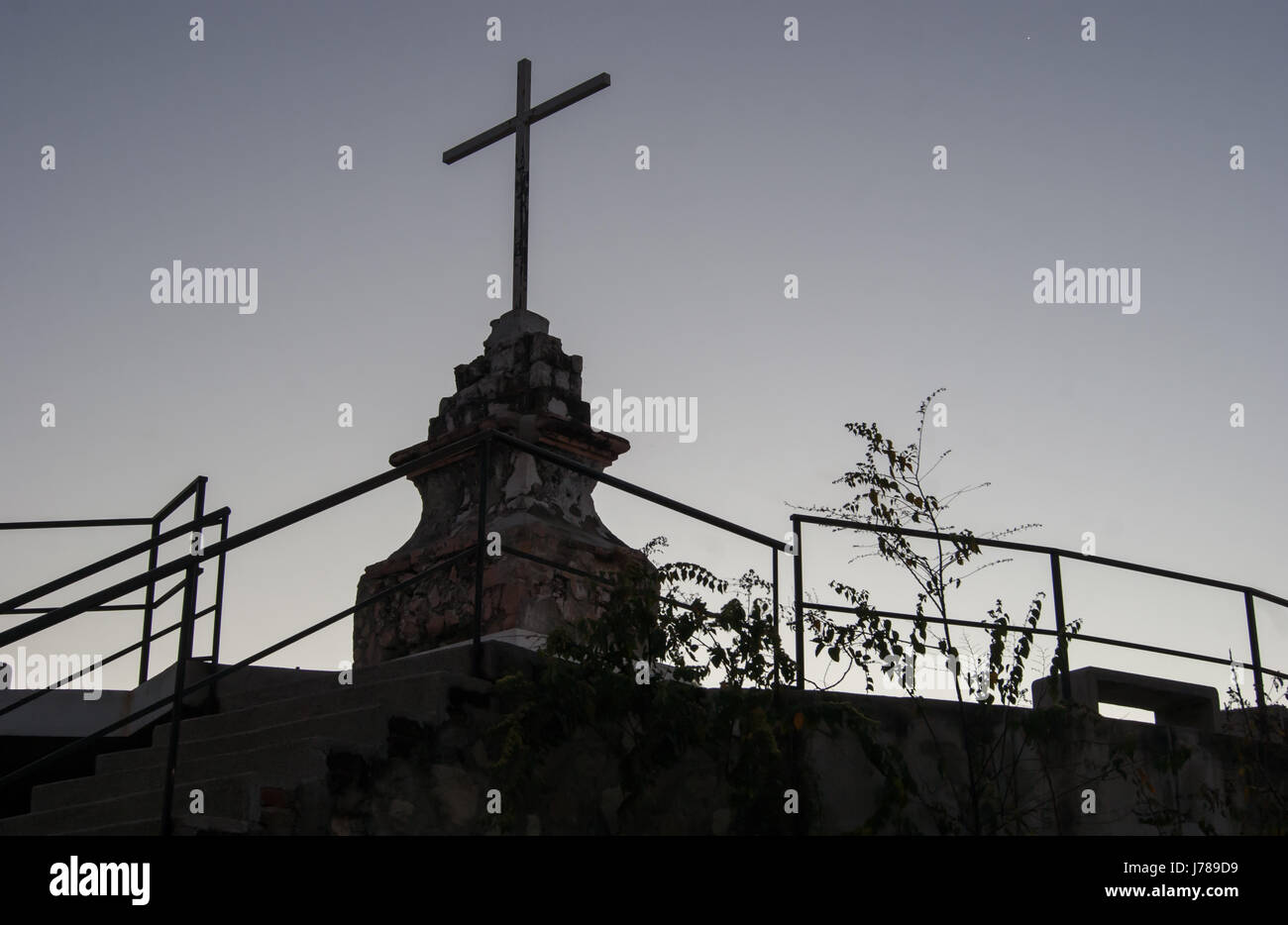La siluette di una croce sulla sua base su una piattaforma di osservazione al tramonto. Un luogo di preghiera e di riflessione Foto Stock
