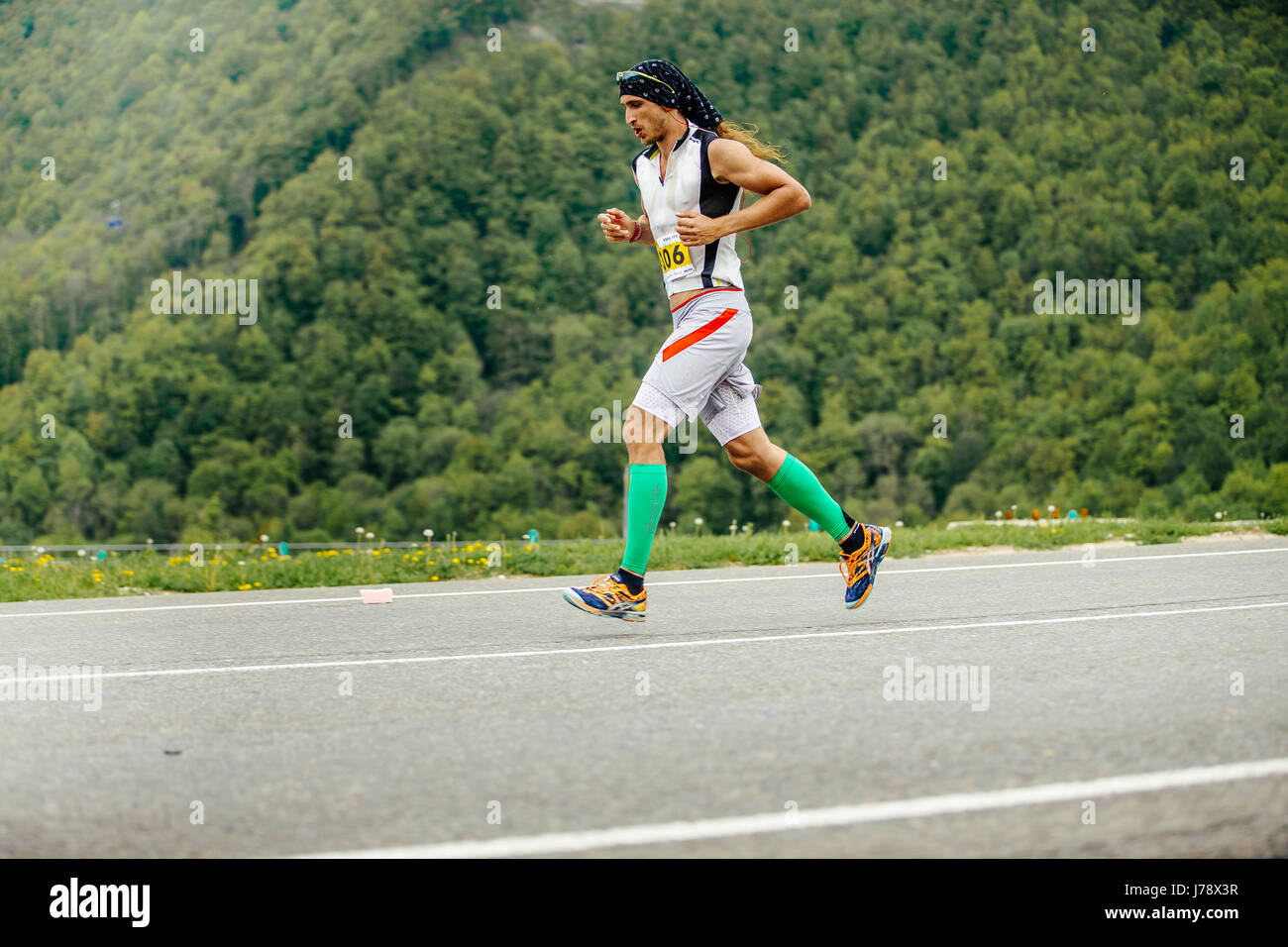Rosa Khutor, Russia - 7 Maggio 2017: maschio runner in esecuzione in calze di compressione sullo sfondo delle montagne e degli alberi in gara Spring Mountain marath Foto Stock