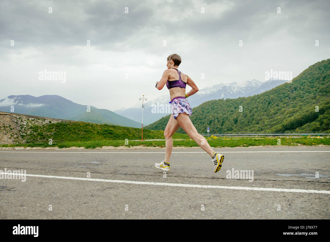 Una donna di mezza età runner in esecuzione su strada asfaltata in gara Spring Mountain marathon Foto Stock