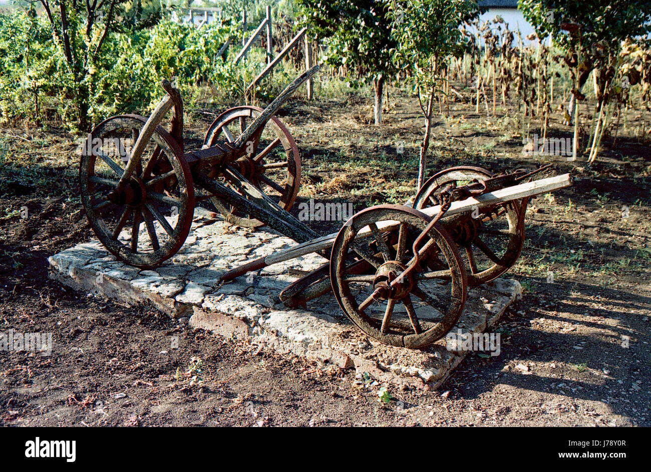 Il vecchio vintage carrello di legno-aratro sorge sulla strada vicino al giardino. Rotto, abbandonati Foto Stock