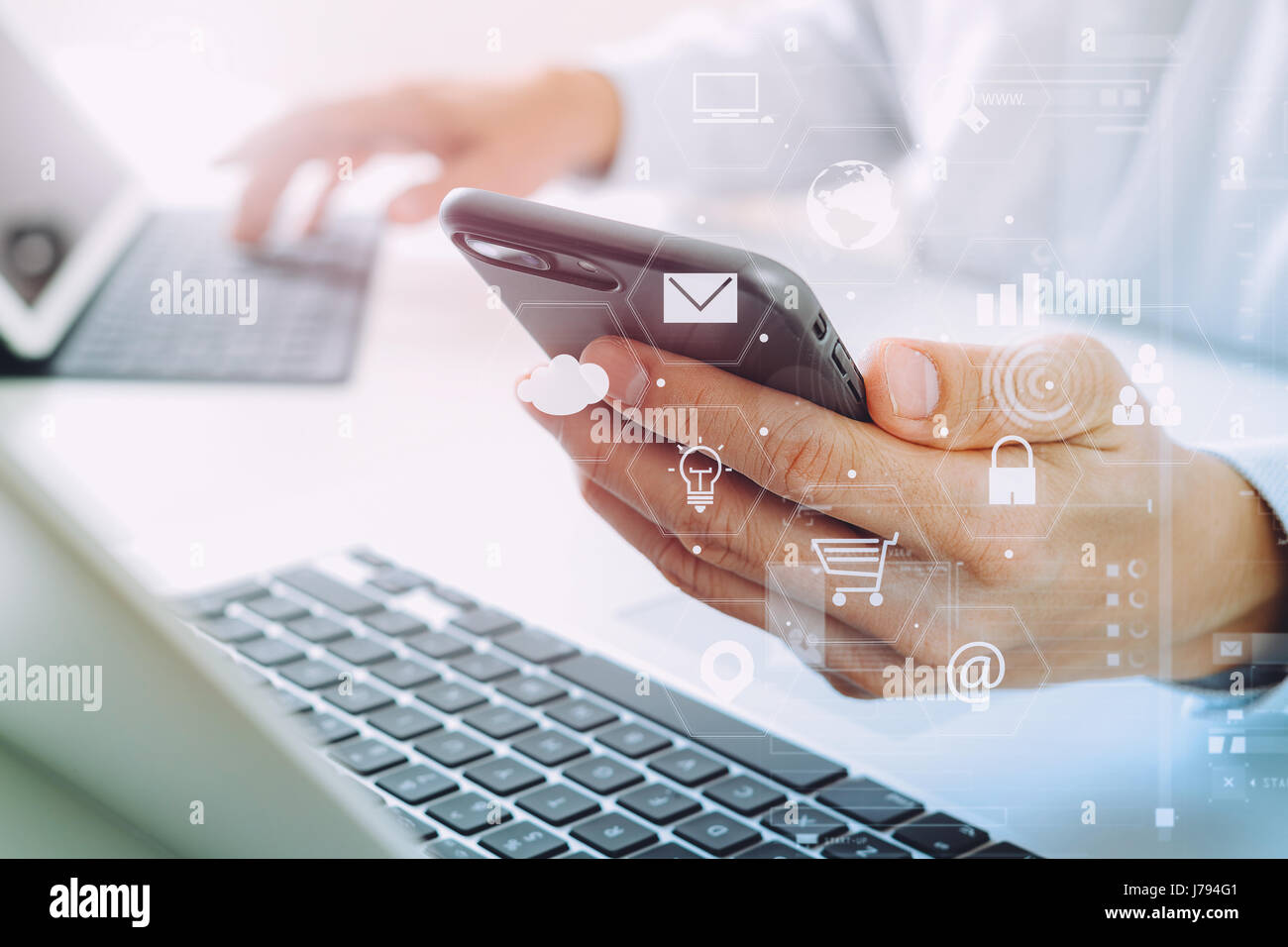 Close up di imprenditore mediante telefono cellulare e computer portatile su bianco scrivania in ufficio moderno con VR schema icone Foto Stock
