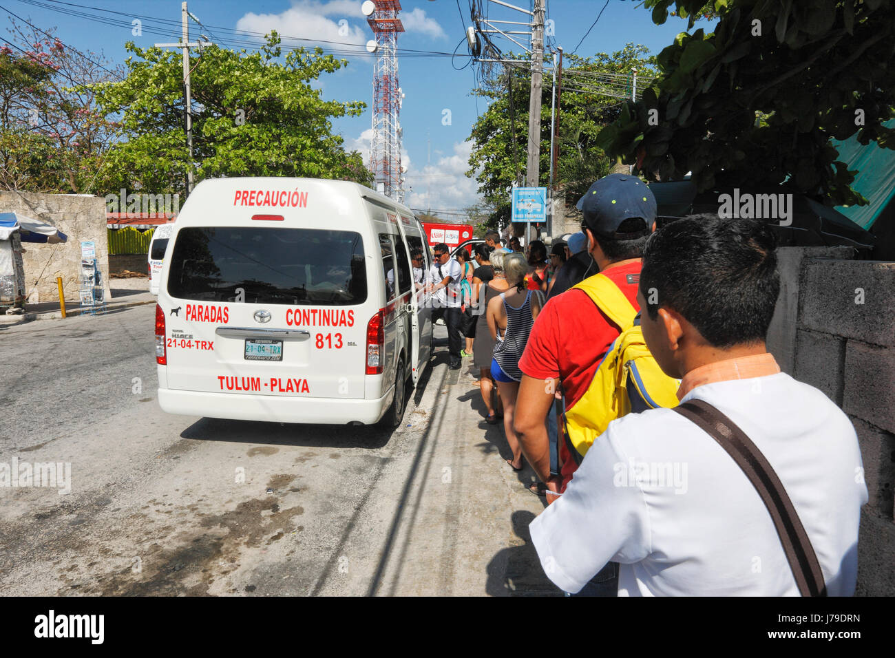 I turisti e i locali di rimanere in linea per il colectivo bus da Playa del Carmen a Tulum Foto Stock