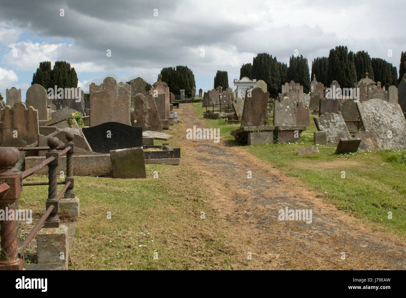 Percorso tra le lapidi in un cimitero vecchio in Newtownards Co Down Irlanda del Nord con alberi in lontananza Foto Stock
