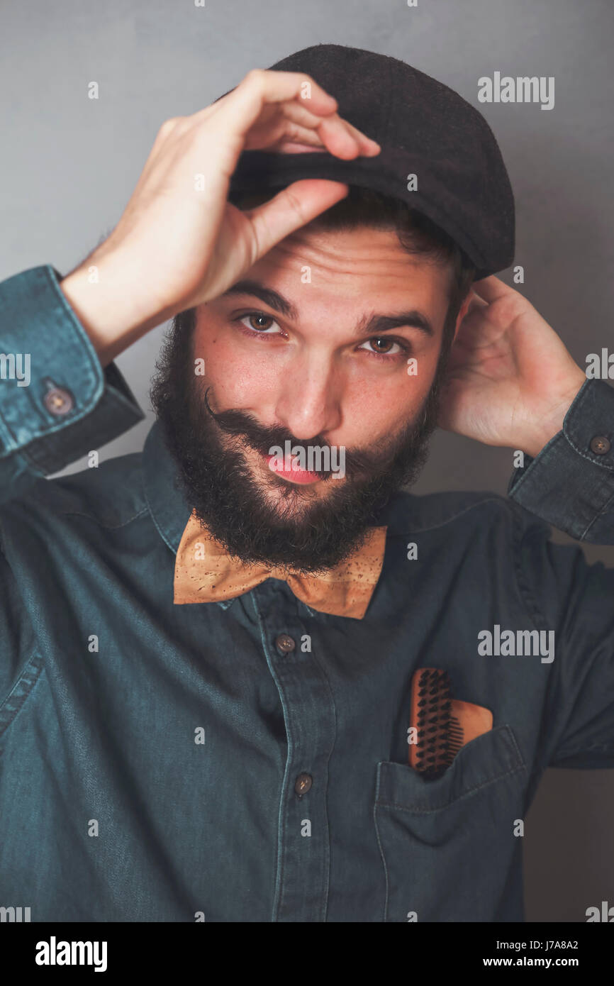 Ritratto di uomo barbuto che indossa il cappuccio, denim shirt, sughero bow tie, indossando i pettini in legno per la barba e baffi in tasca Foto Stock