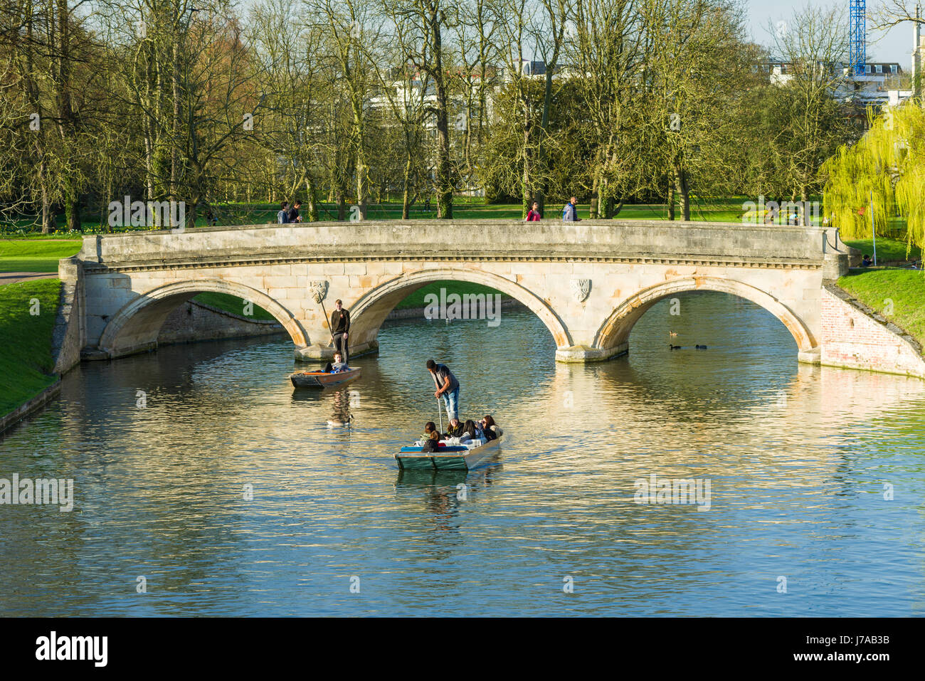 I turisti su Punt barche con il ponte di pietra sul fiume Cam su una soleggiata giornata di primavera, Cambridge, Regno Unito Foto Stock