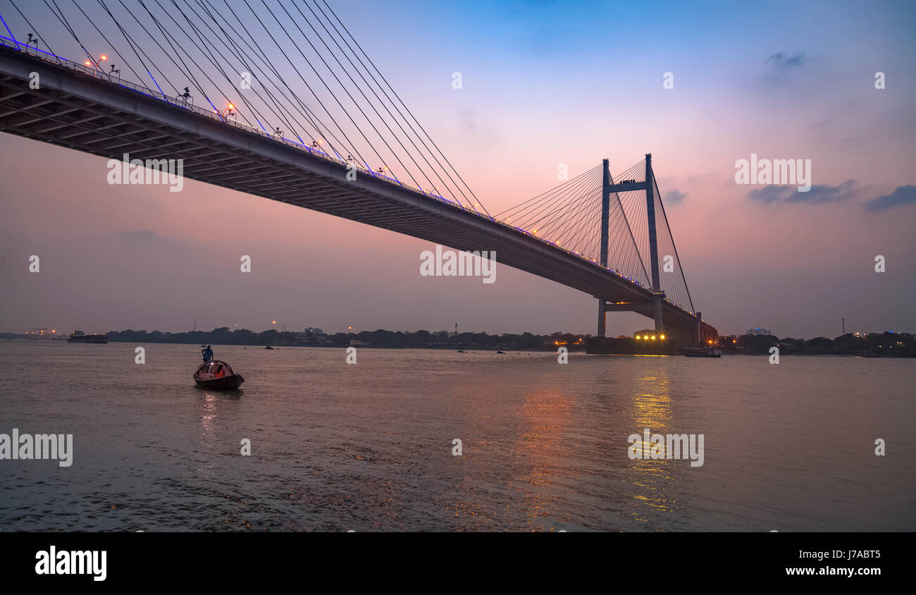 Setu vidyasagar bridge al crepuscolo con una barca di legno sul Fiume Hooghly. Foto Stock