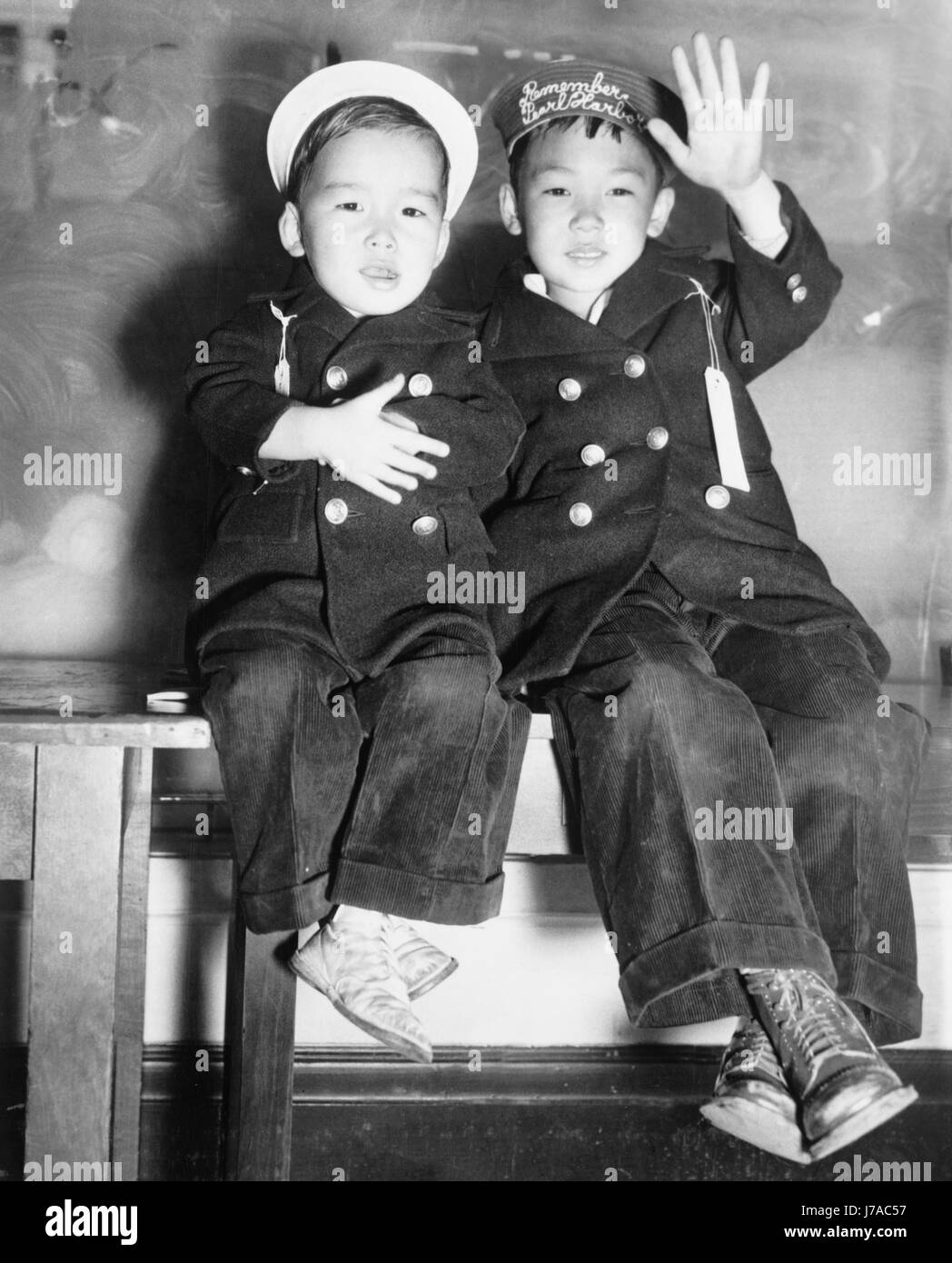Due ragazzi Japanese-American attendere un bus per portarli ad un campo di internamento, 1942. Foto Stock