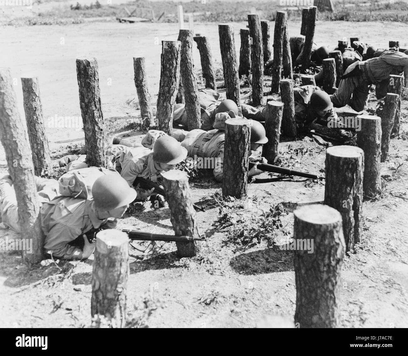 Soldati strisciare attraverso un ostacolo di registri di pino a Camp Edwards, Massachusetts, circa 1942. Foto Stock