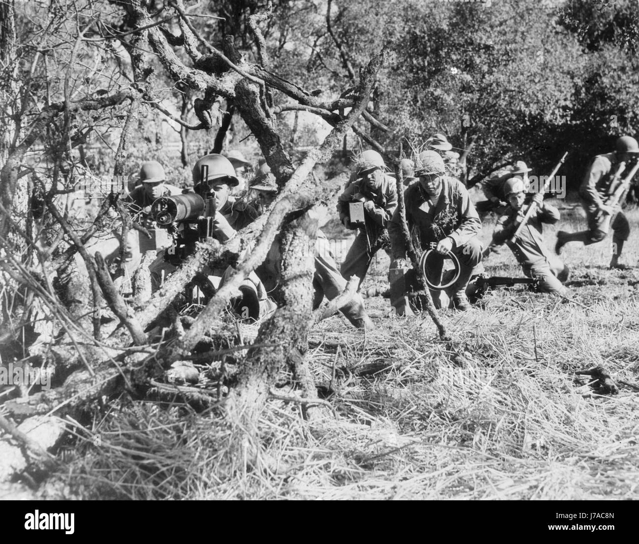 Stati Uniti Army mitragliatrice equipaggio la protezione di avanzamento di soldati a piedi, circa 1942. Foto Stock