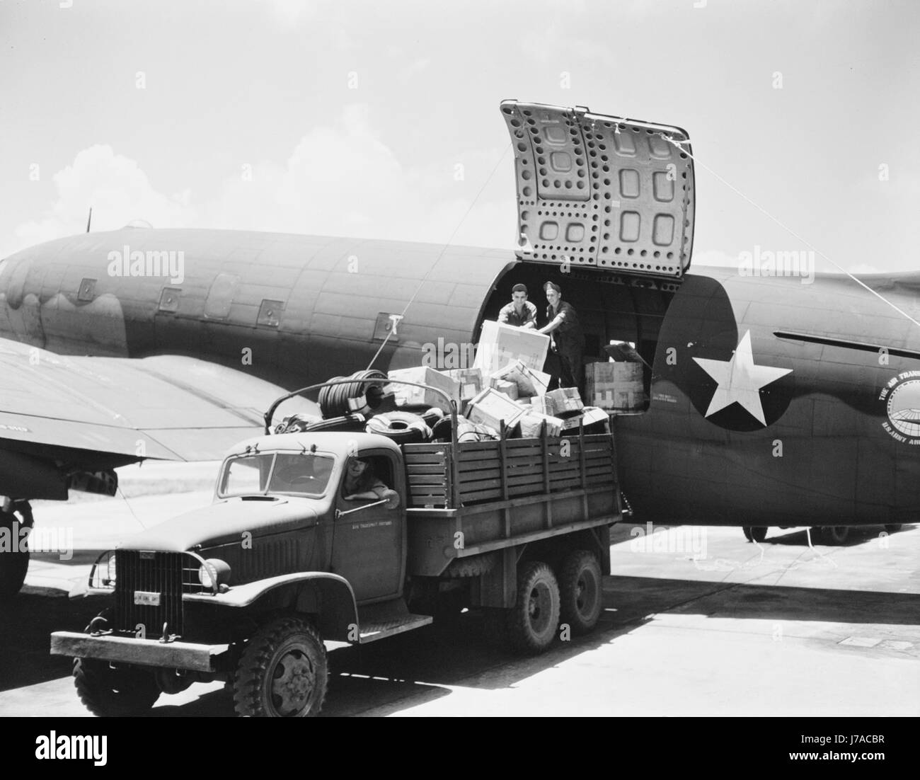 Lo scarico del carico da un U.S. L'esercito dell'aria di comando di trasporto aereo cargo, circa 1943. Foto Stock