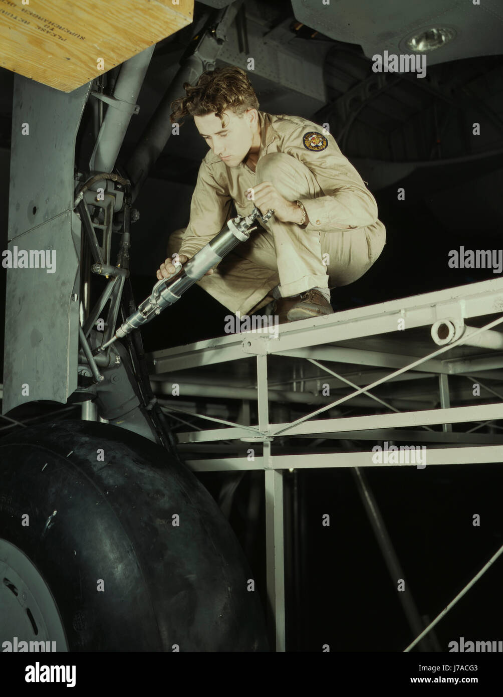 Un meccanico di ingrassaggio carrello di atterraggio di un piano di trasporto, 1942. Foto Stock