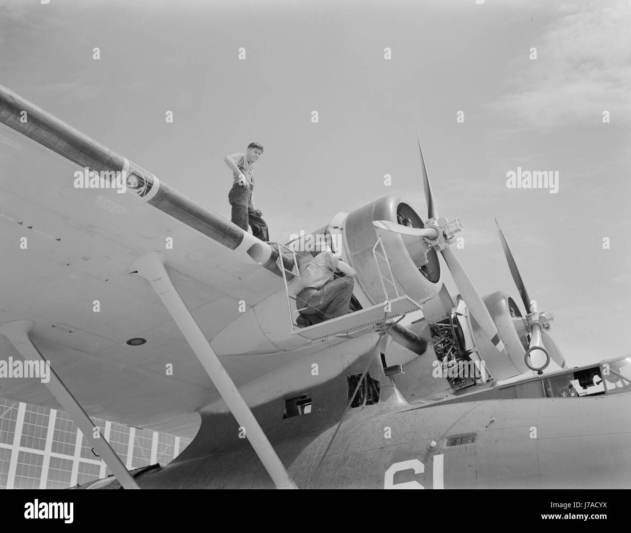 La meccanica di aviazione controllare l'enorme motore su un U.S. Navy costruttiva PBY battenti nave, 1942. Foto Stock