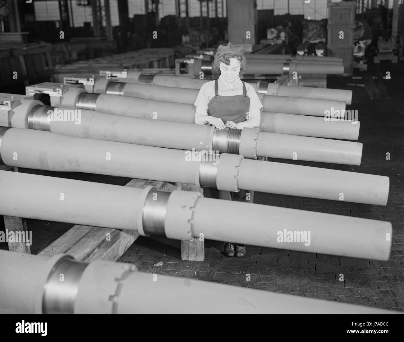 Donna ispezione di uno dei 25 frese per sbavature prima di metterlo in un 105mm obice. Foto Stock