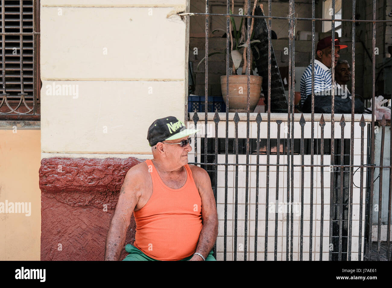 Il vecchio uomo cubano seduti sulle strade di l'Avana con una New York berretto da baseball Foto Stock