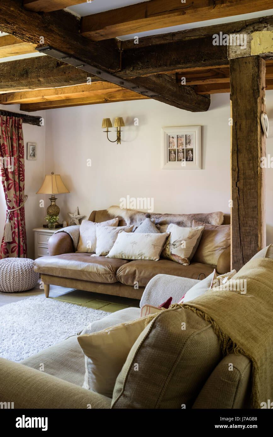 Accogliente salotto con travi di legno sul soffitto. Il divano in pelle è da focaccia e il tappeto da John Lewis Foto Stock