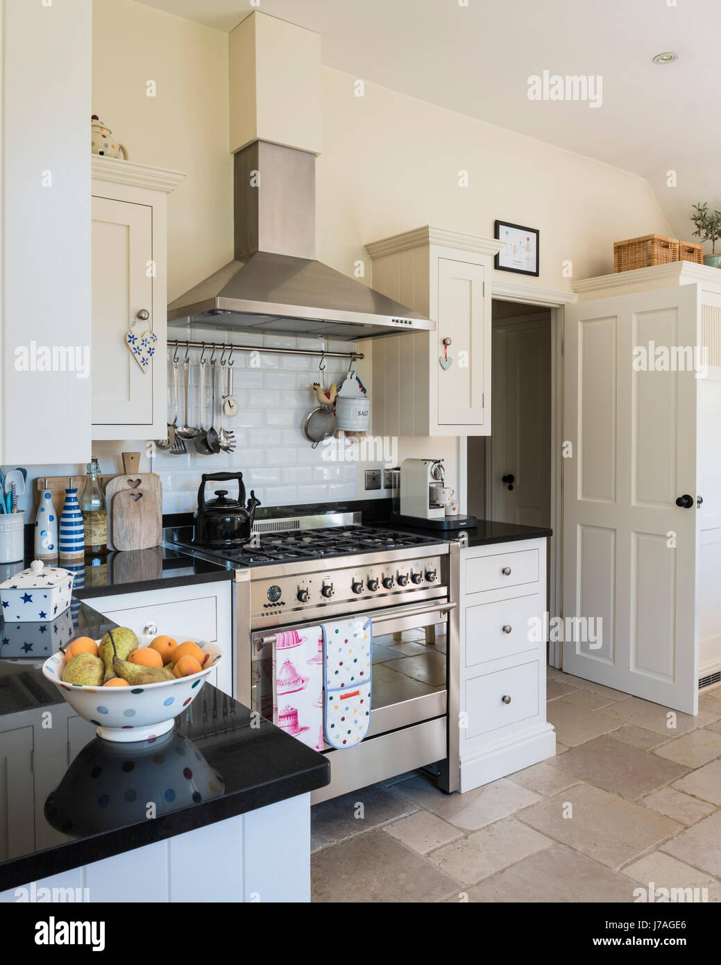 Spaziosa cucina a pianta aperta con Smeg termocucina e rustico piastrelle per pavimento. Le unità sono dipinte in terra cotti Il Gelso Bianco guscio d'uovo Foto Stock