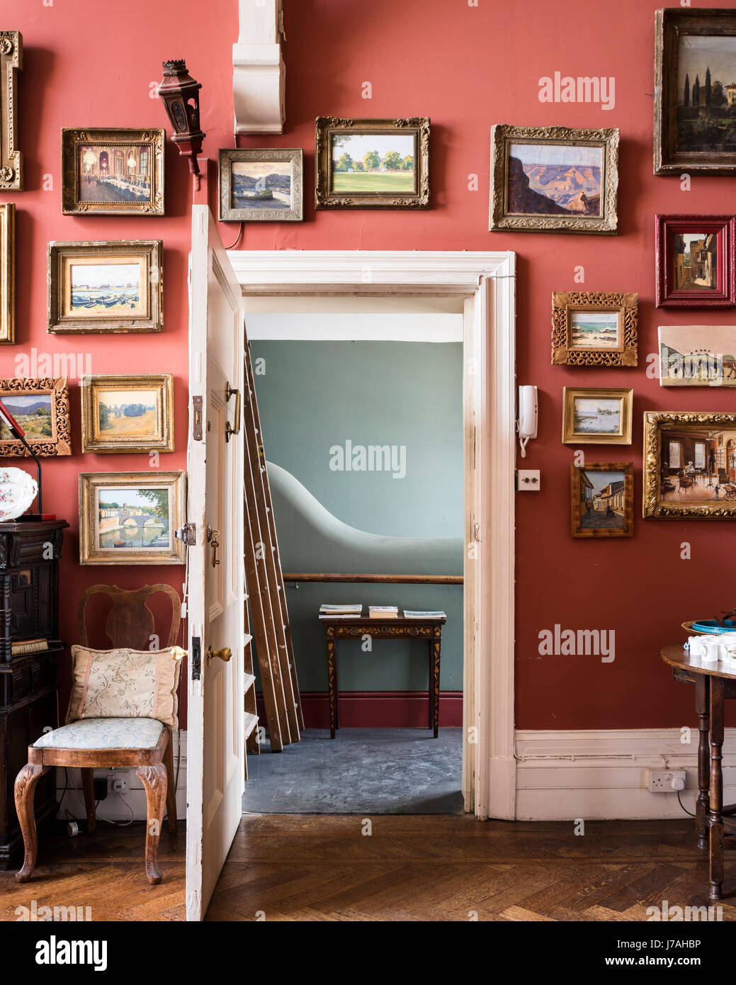Una collezione di Julian Barrow dipinti sono appeso attorno alla porta via con vista attraverso di sbarco Foto Stock
