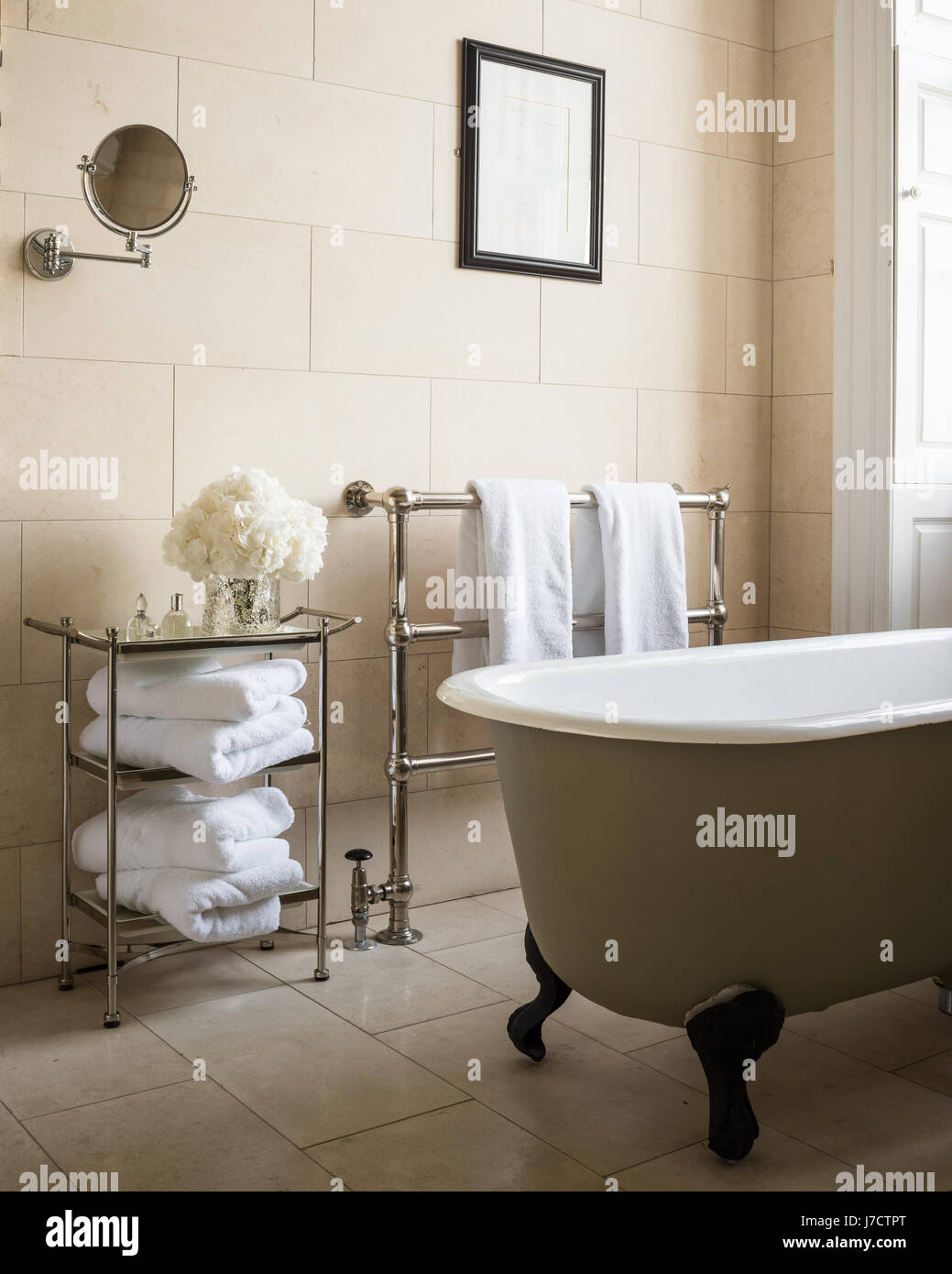 Recuperati free-standing vasca da bagno e asciugamani in bagno con parete e pavimento di piastrelle da Purpletree Foto Stock