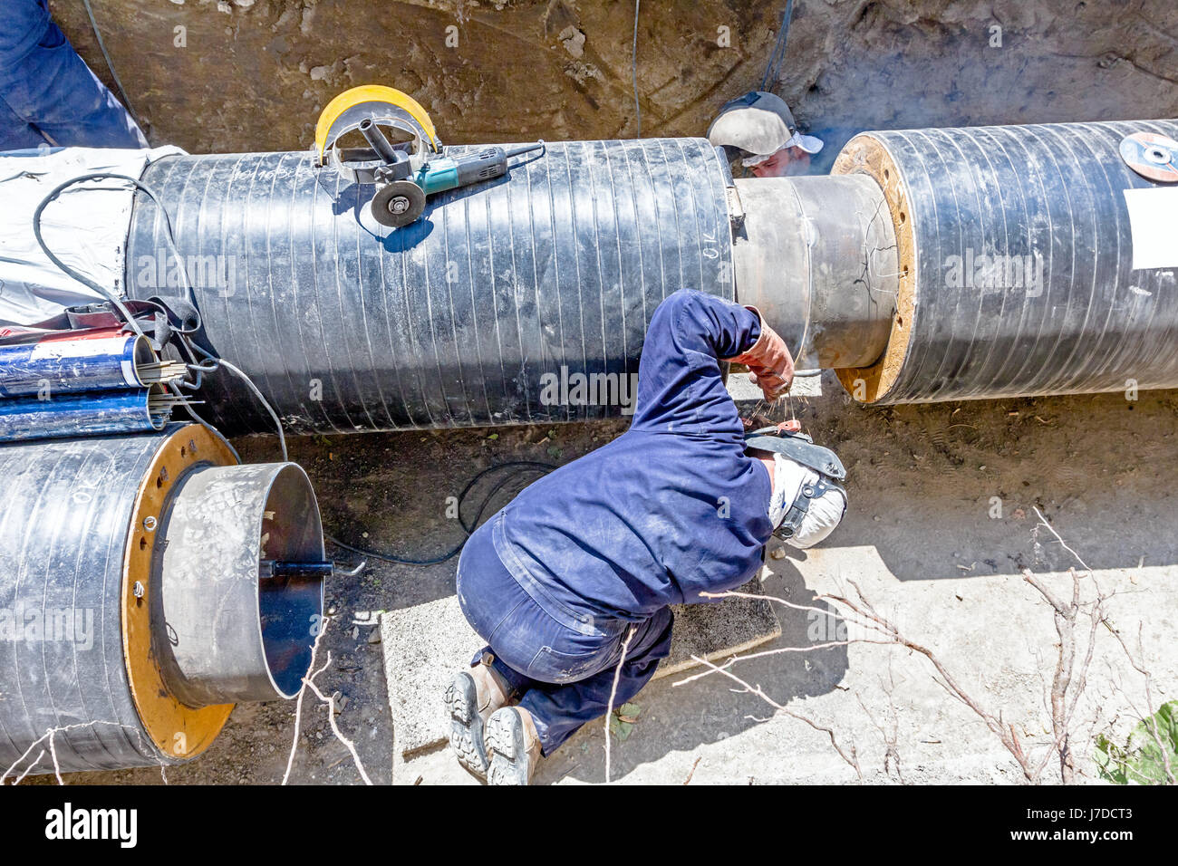 Il team di saldatori è in trincea lavorando duro per installare un nuovo gasdotto. Saldatura ad arco tubi Foto Stock