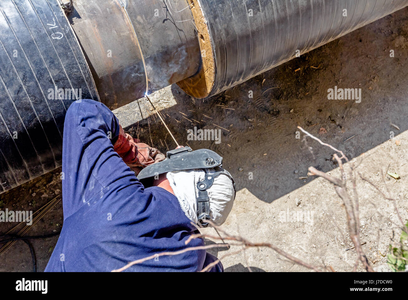 Saldatrice è in trincea lavorando sodo, saldatura ad arco pipeline. Foto Stock