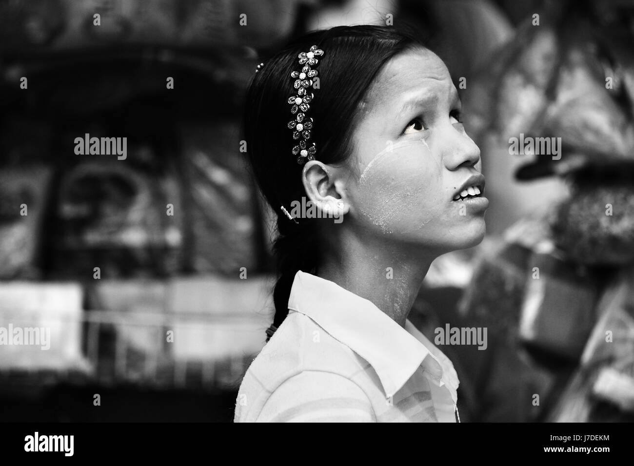 Bella alto contrasto foto in bianco e nero di Myanmar ragazza cercando skywards in monocromatico. Ragazza birmano indossando alice band nei capelli di Yangon Foto Stock