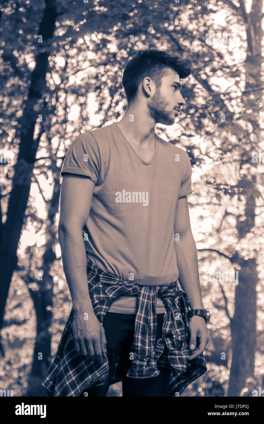 Un giovane uomo adulto, solo guardando lontano, parco natura alberi all'aperto, immagine in bianco e nero Foto Stock