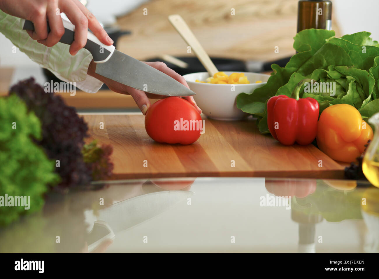 Primo piano delle mani dell uomo di cucina insalata di verdure in cucina sul tavolo di vetro con la riflessione Foto Stock