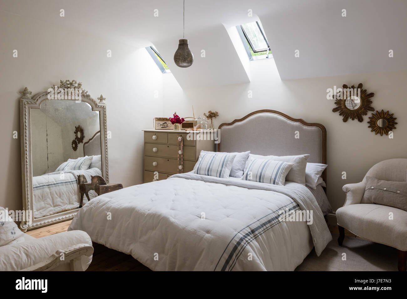 Ornati specchio francese in camera per ospiti con letto da piuma & Nero. Le pareti sono dipinte di scrematura di pietra da Farrow & Ball Foto Stock