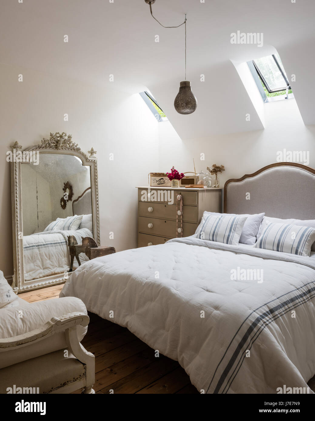 Ornati specchio francese in camera per ospiti con letto da piuma & Nero. Le pareti sono dipinte di scrematura di pietra da Farrow & Ball Foto Stock