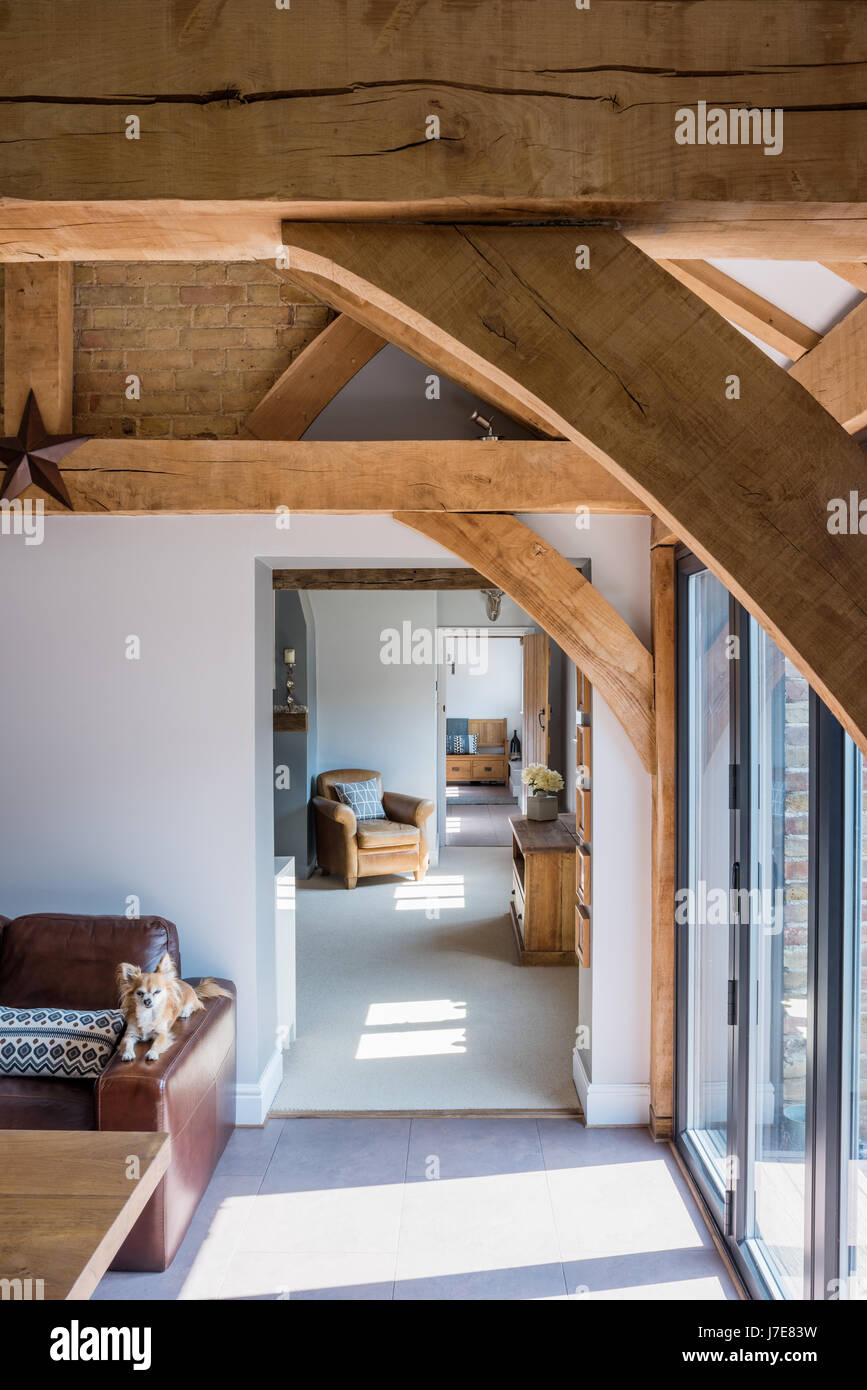 Vista dalla quercia incorniciato cucina attraverso al soggiorno con poltrona in pelle Foto Stock
