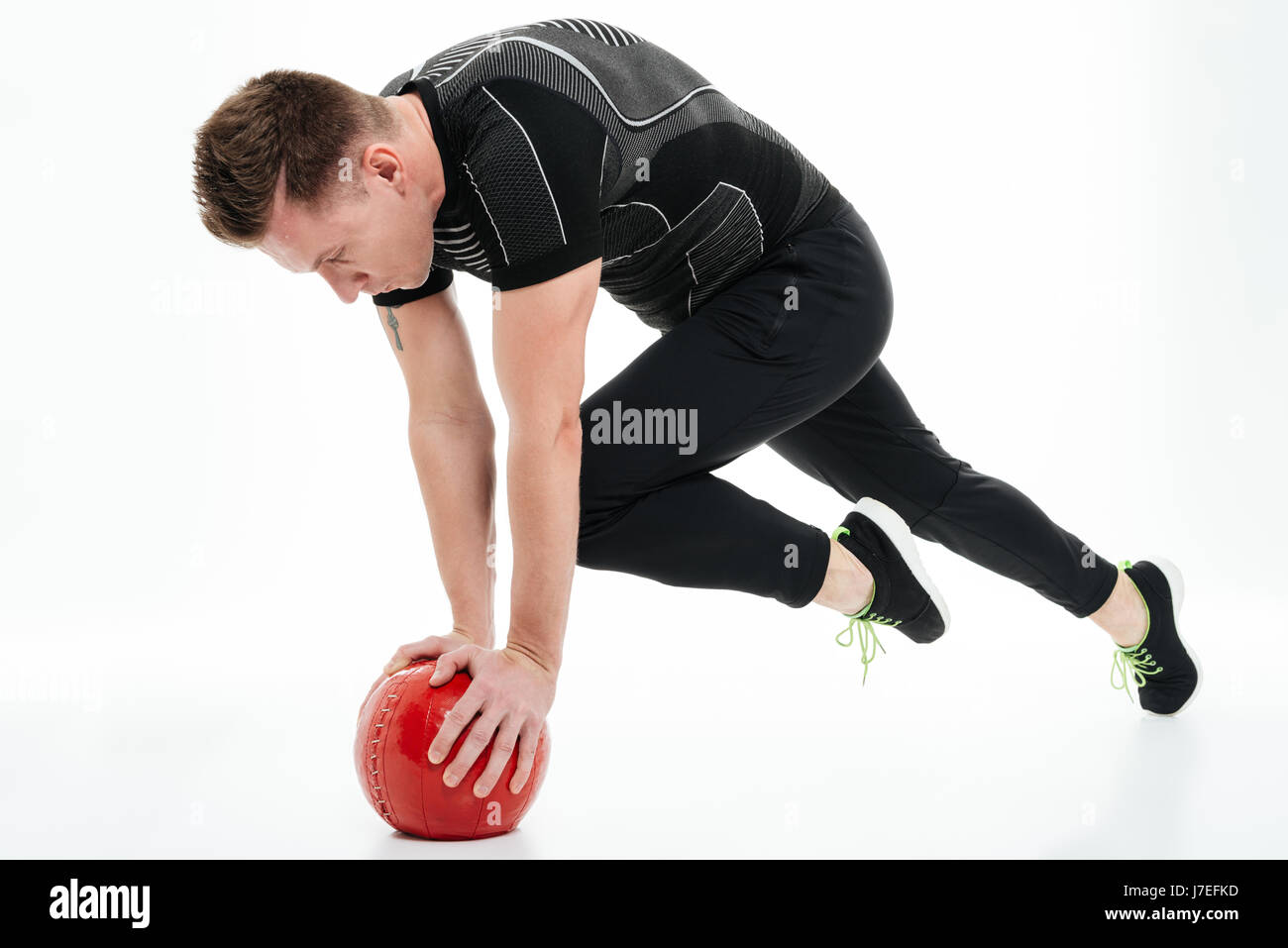 A piena lunghezza Ritratto di un atleta concentrato l uomo a fare gli esercizi con la pesante palla fitness isolate su sfondo bianco Foto Stock