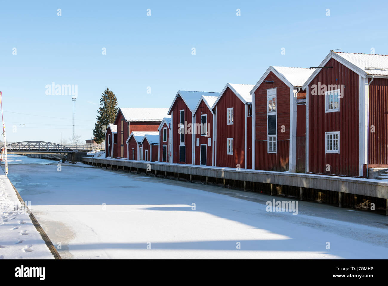 Tradizionali barche rosse in legno lungo il porto ghiacciato di Hudiksvall, in Svezia, in una giornata invernale limpida e soleggiata. Foto Stock