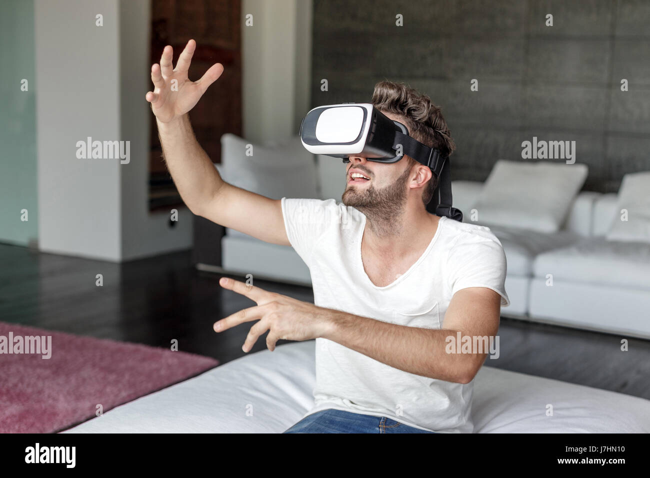 Giovane uomo informale giocando su occhiali VR indoor Foto Stock