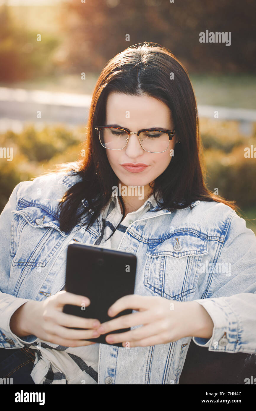 Giovane donna preoccuparsi di false notizie di leggere su tablet Foto Stock