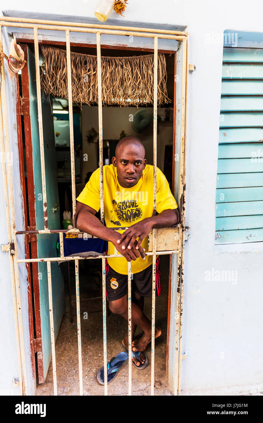 Giovani Afro uomo cubano guardando fuori dalla sua casa a La Havana Cuba, la povertà a Cuba, povertà cubano, povero uomo cubano, cubana home, case di Cuba, La Habana home Foto Stock