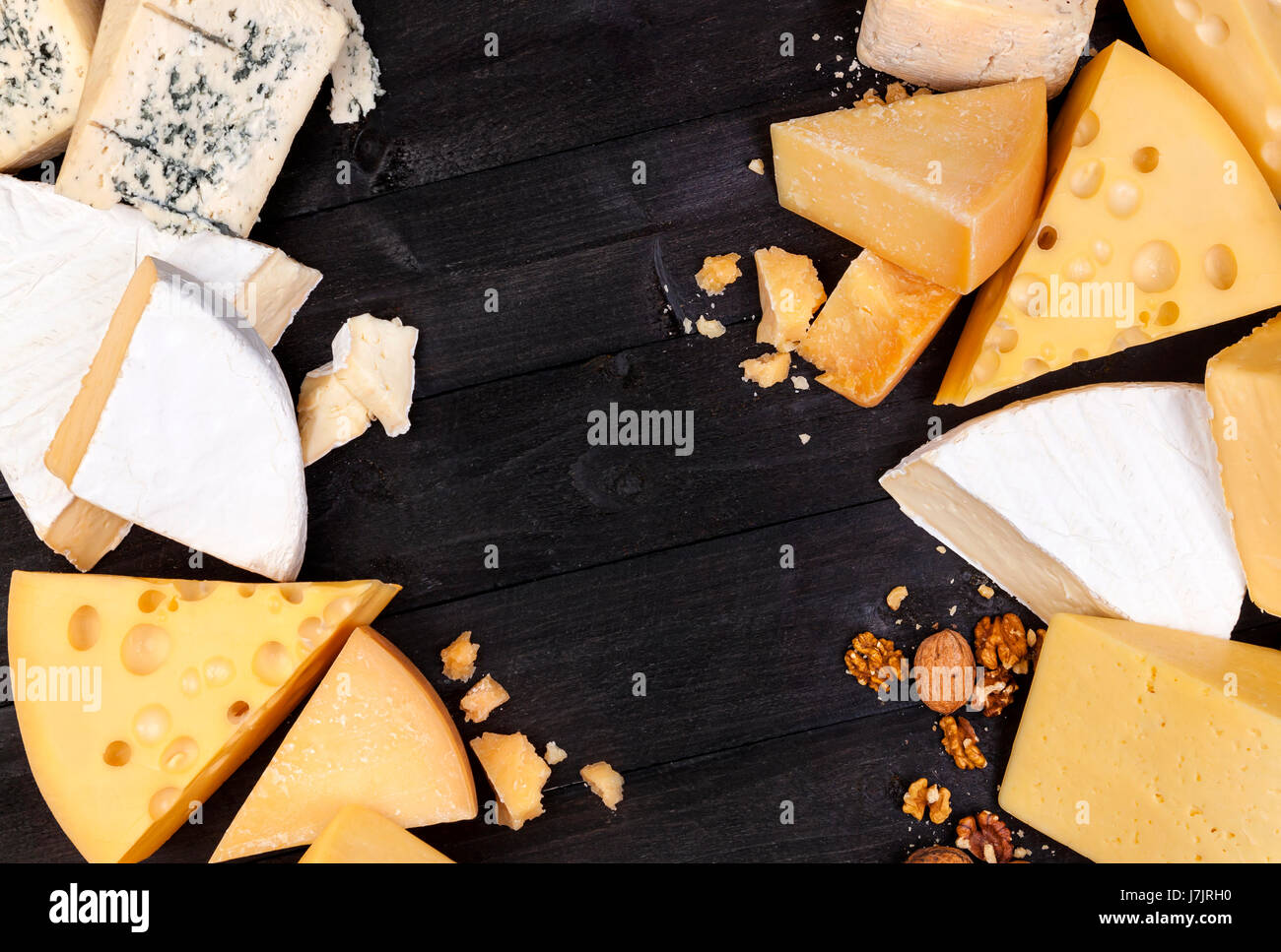 Vari tipi di formaggio su tavoli in legno nero lo sfondo. Il Cheddar, parmigiano, emmental, formaggi blu. Vista superiore, copia dello spazio. Foto Stock