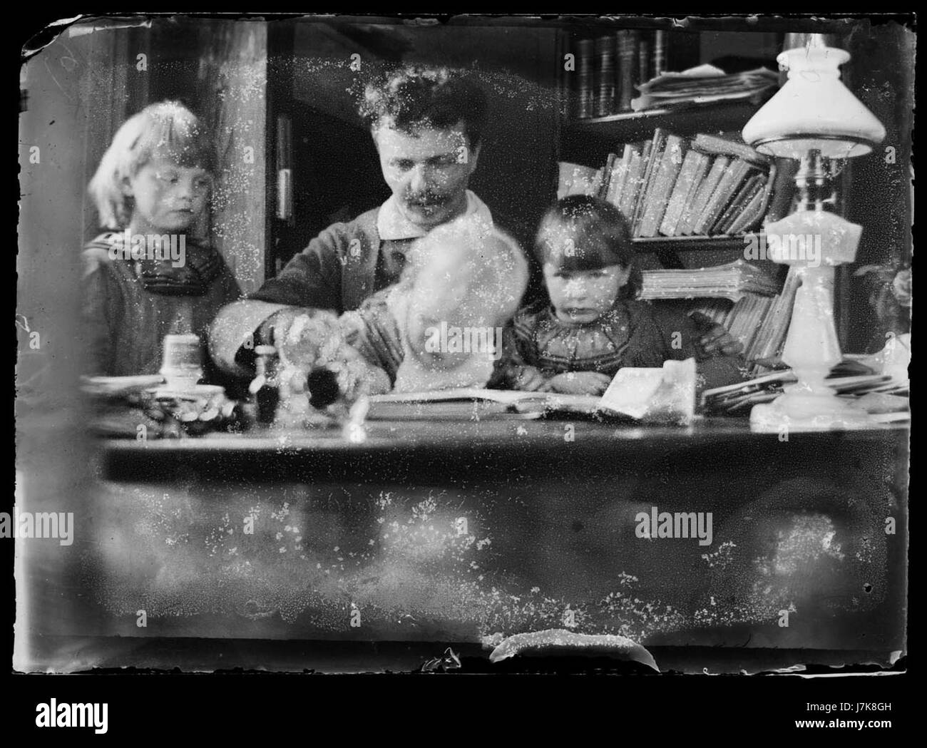 Questa immagine raffigura il drammaturgo svedese August Strindberg con i suoi figli a una scrivania a Gersau, in Svizzera, un momento personale catturato nel XIX secolo. Strindberg è noto per le sue opere che esplorano la natura umana e le questioni sociali. Foto Stock