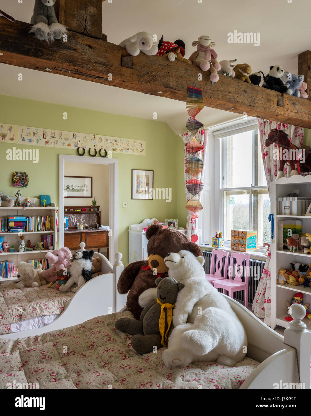 Piumino floreale su bambini letti singoli in una camera piena di giocattoli di peluche Foto Stock
