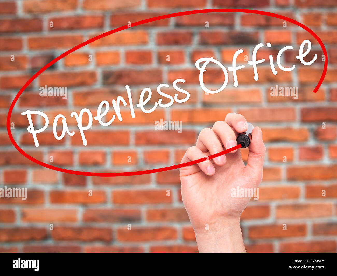 Man mano che scrive paperless office con un pennarello nero su schermo visivo. Isolato su mattoni. Business, tecnologia internet concetto. Stock Photo Foto Stock