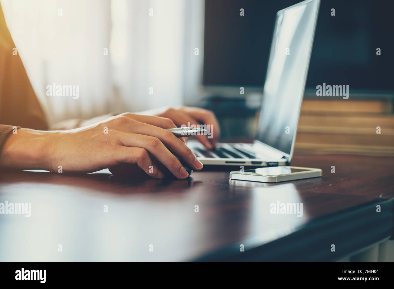 Lato business man tenendo premuto il mouse e utilizzando computer portatile in ufficio. Effetto vintage. Foto Stock