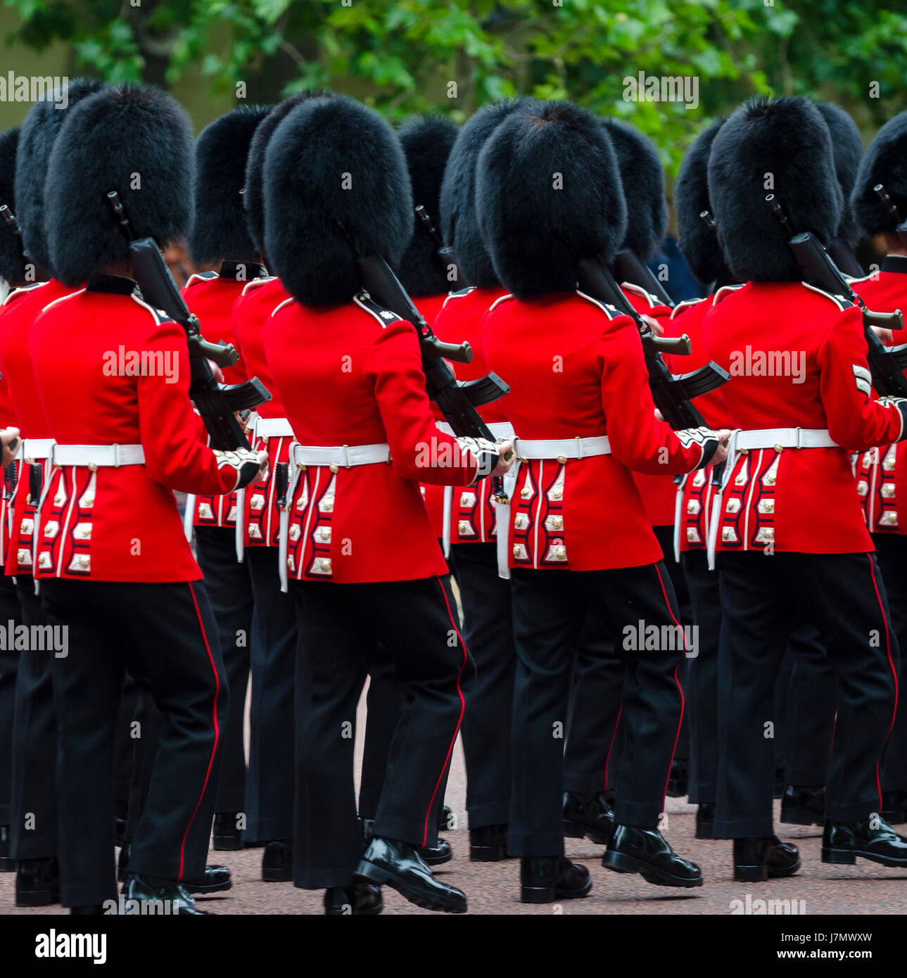 I soldati in rosso classico di cappotti e pellicce orso busby headwear marzo lungo il Mall a Londra in Inghilterra in un grand Trooping il colore spettacolo Foto Stock