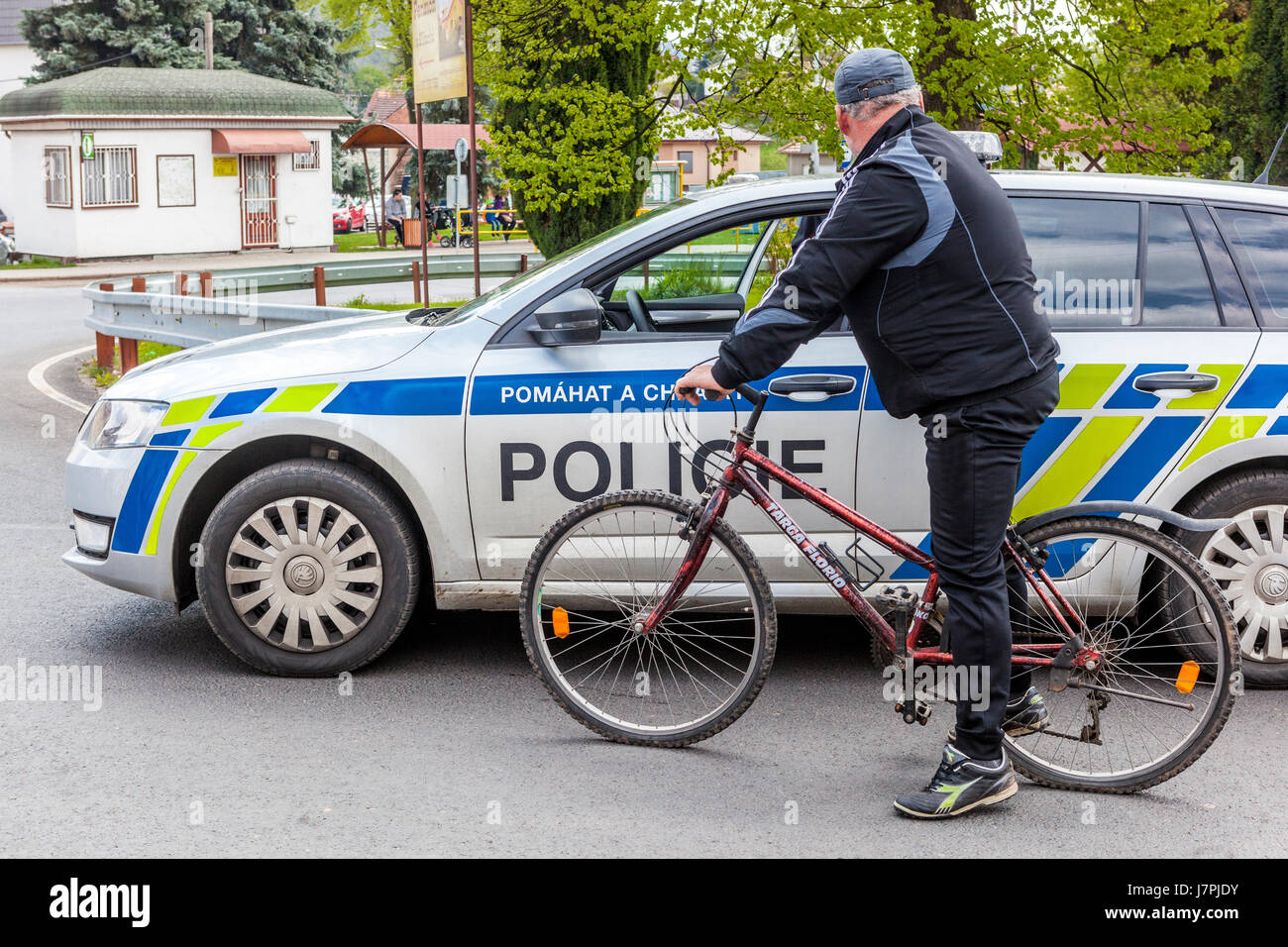 Ciclista su una bicicletta fermata a una macchina di polizia, Repubblica Ceca vita quotidiana Europa Foto Stock