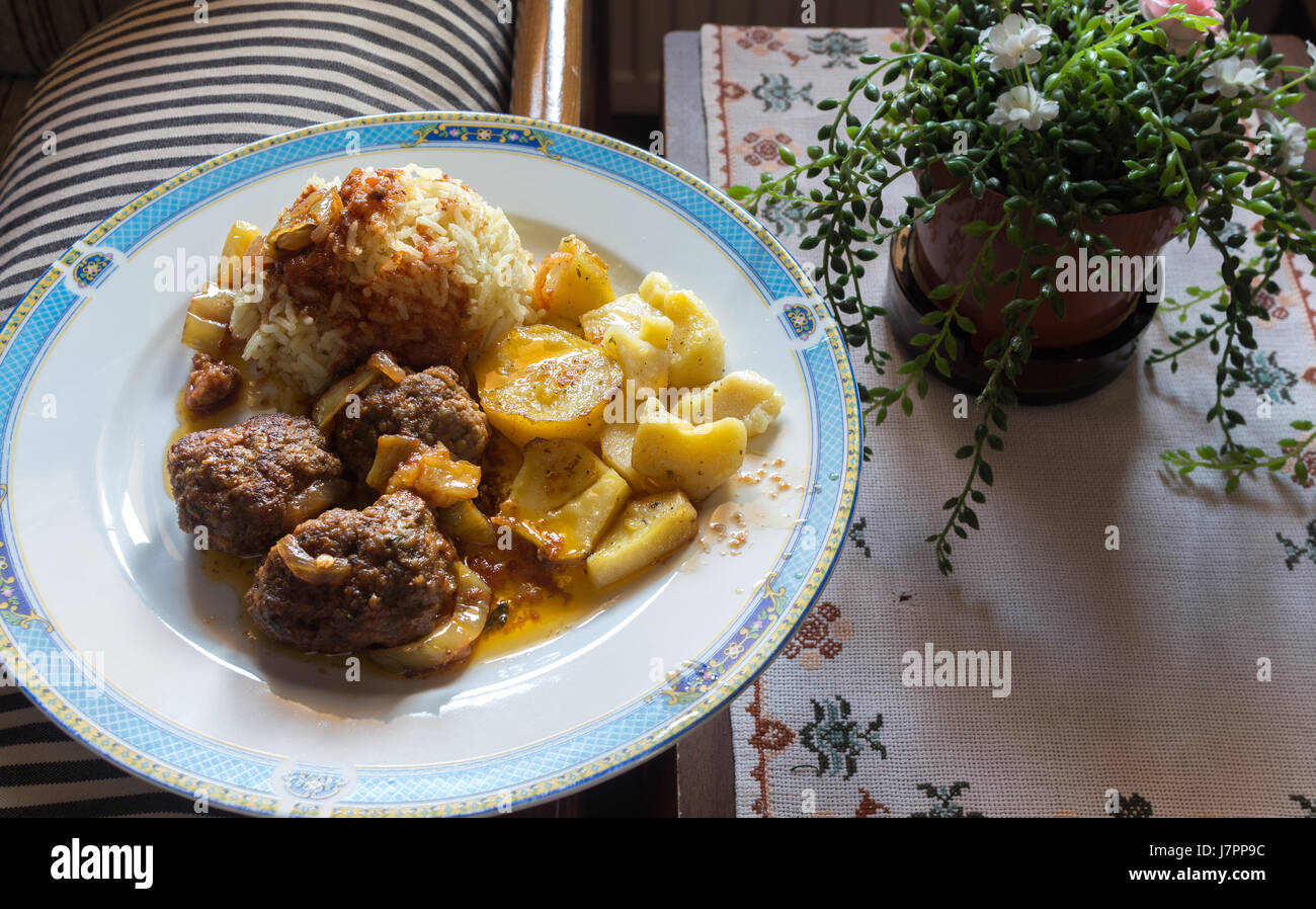 Un piatto di cibo fatta a mano con patate, polpette di carne e riso, posto sul salotto di casa. Foto Stock