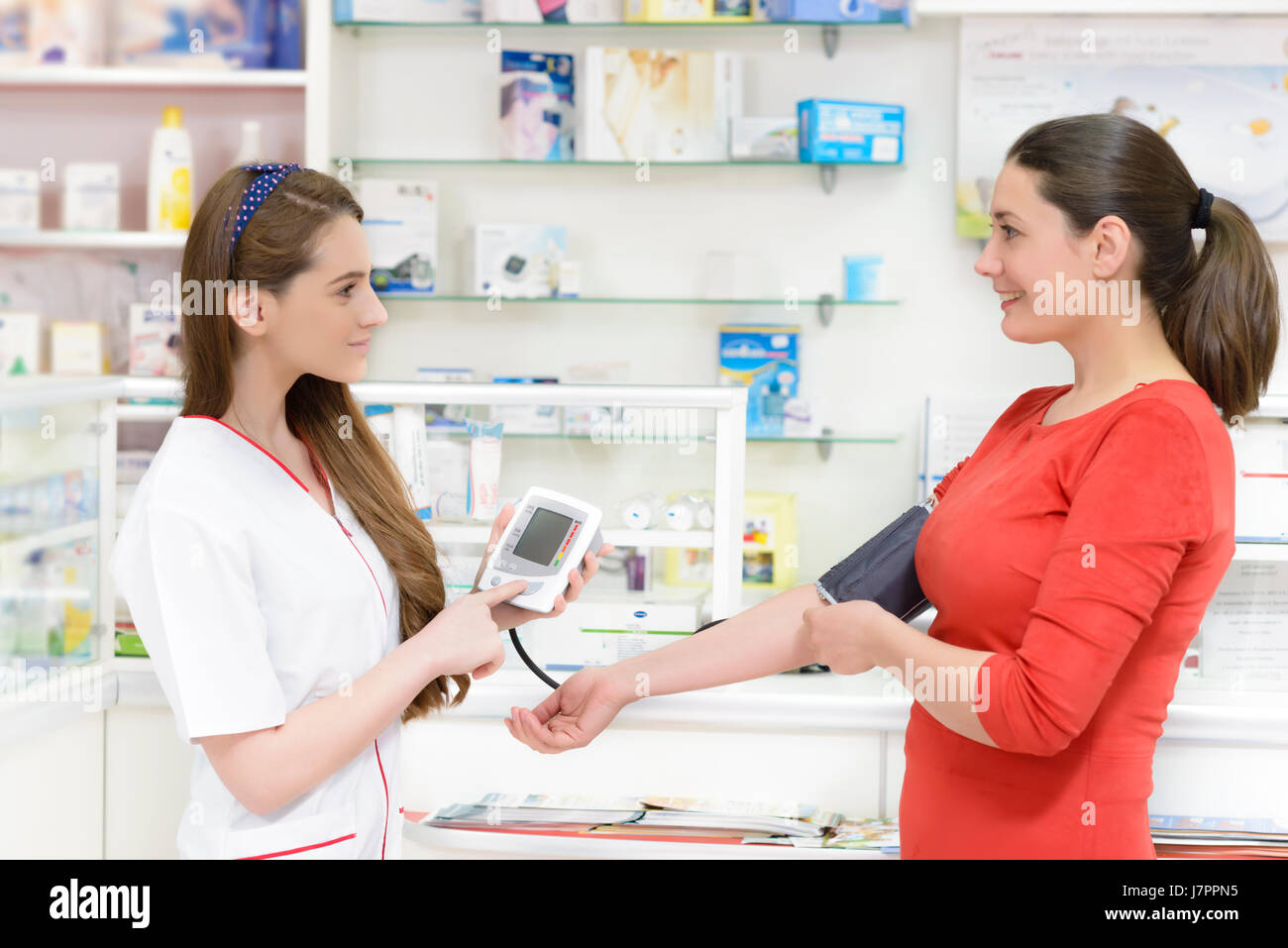 Il farmacista che mostra un digital misurazione pressione sanguigna periferica a un cliente Foto Stock