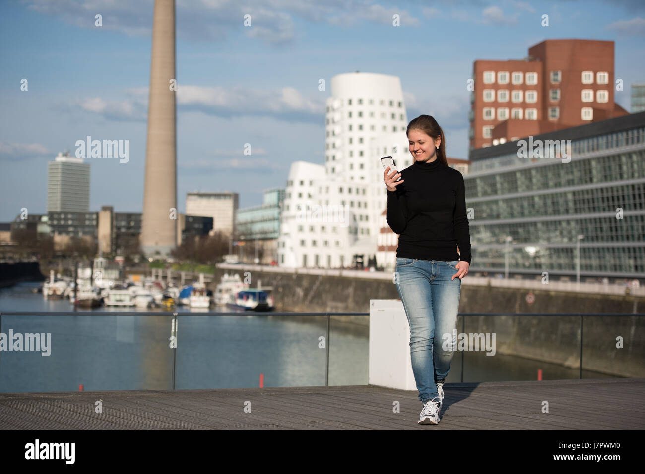 Giovane donna in nero pullover con lo smartphone nella parte anteriore di edifici aziendali a Duesseldorf in Germania Foto Stock Giovane donna in nero pullover con lo smartphone nella parte anteriore di edifici aziendali a Duesseldorf in Germania Foto Stock