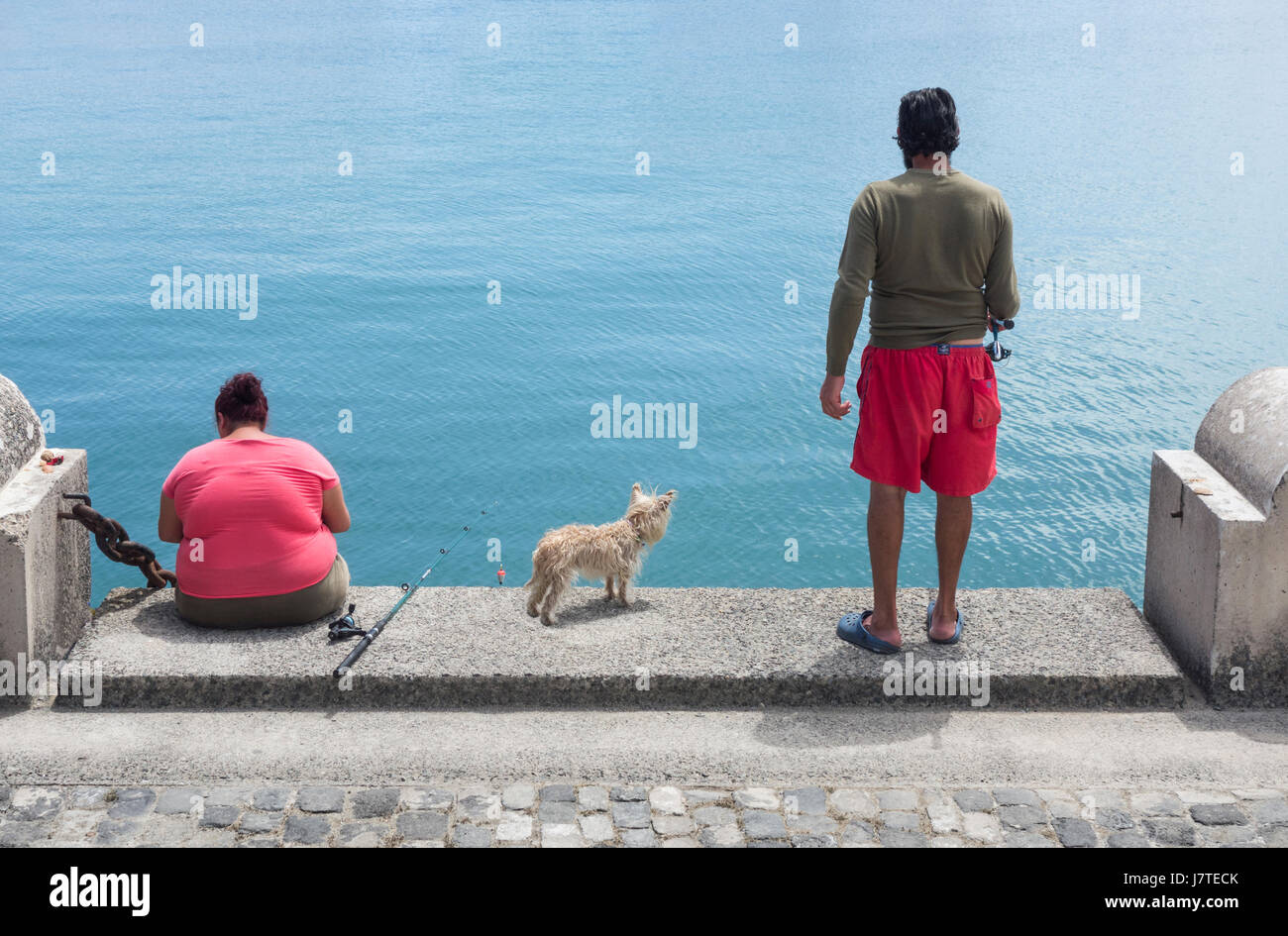 Paio di pesca sul dockside in Spagna. Cane in centro. Foto Stock