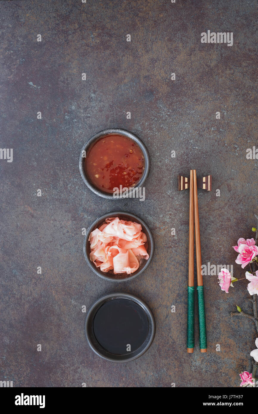 Sushi set. I sushi giapponesi Le bacchette, soia e salsa di peperoncino ciotola e zenzero sott'aceto su pietra scura sullo sfondo Foto Stock